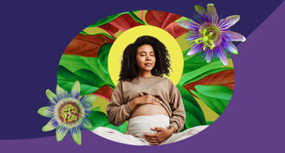 Pregnant woman sitting cross-legged and resting her hands on her stomach, which is partially exposed to show that she is pregnant.