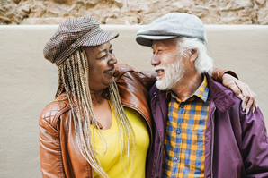 Two smiling adults embrace one another as they greet each other.