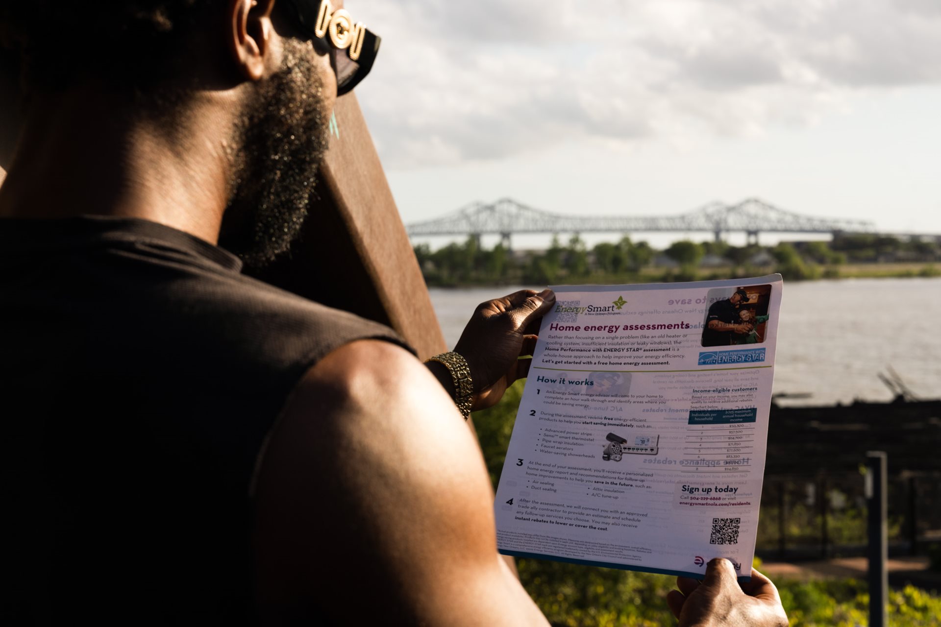 Man standing by the Mississippi River reading about the Energy Smart Program